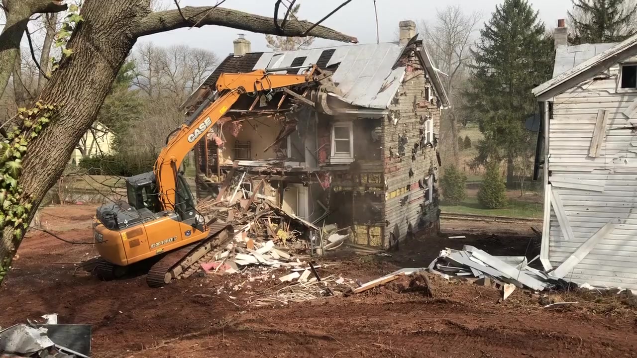 Excavator carrying out structural demolition of a house